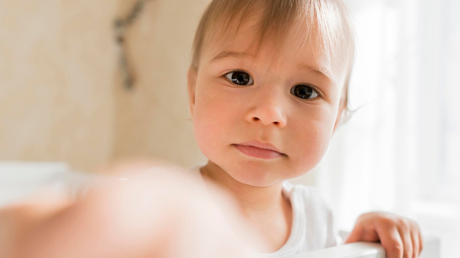 A baby looks curiously from a crib, highlighting early signs of astigmatism parents should observe.