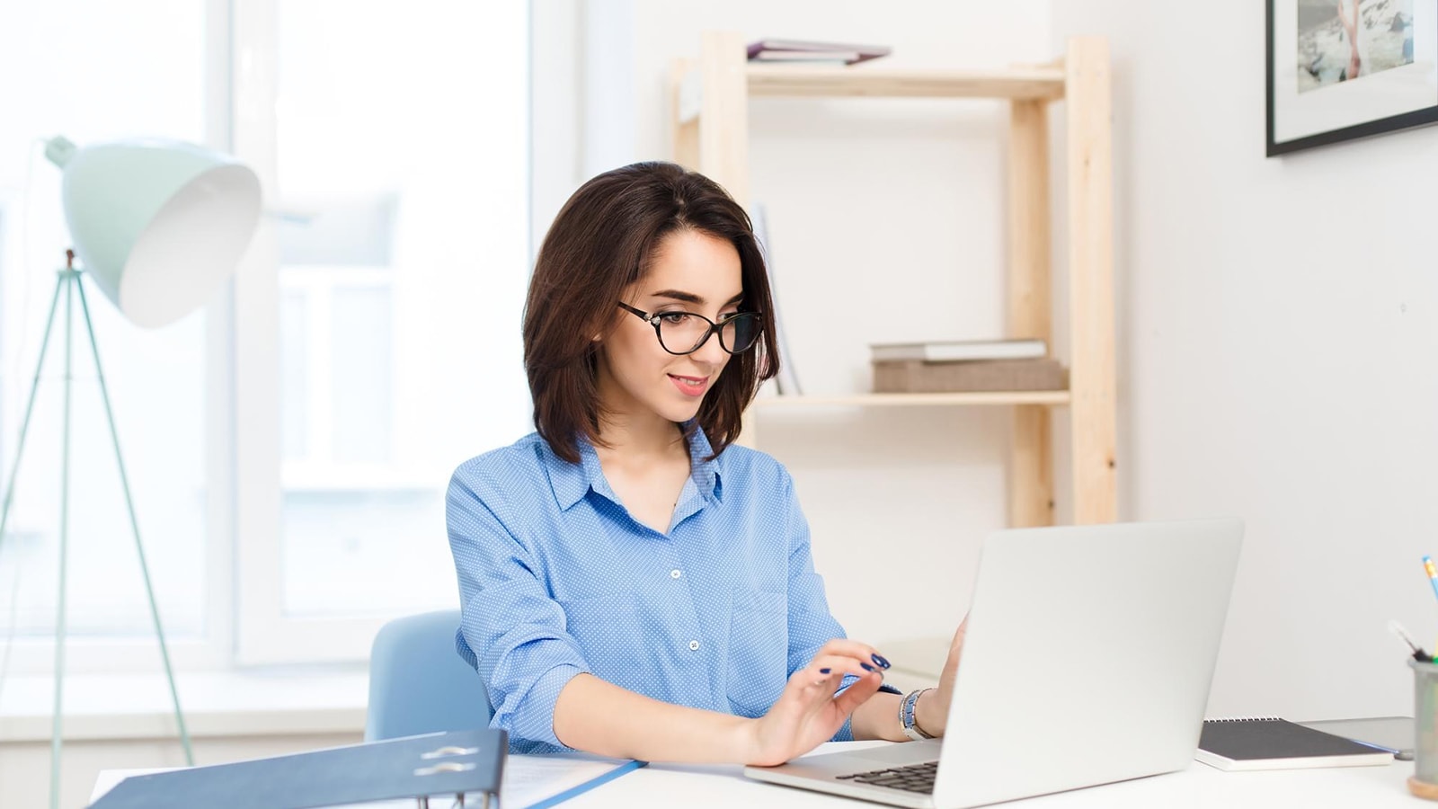 Woman wearing clear glasses using laptop to reduce digital eye strain and improve focus.