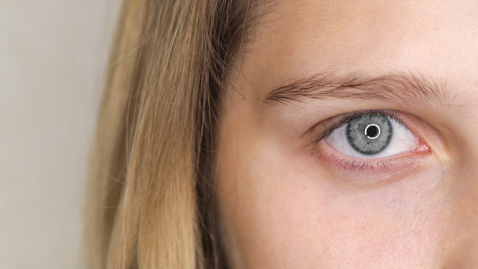 A very close-up shot of a person's eye, showing a distinct gray iris with a dark limbal ring and a small black pupil.