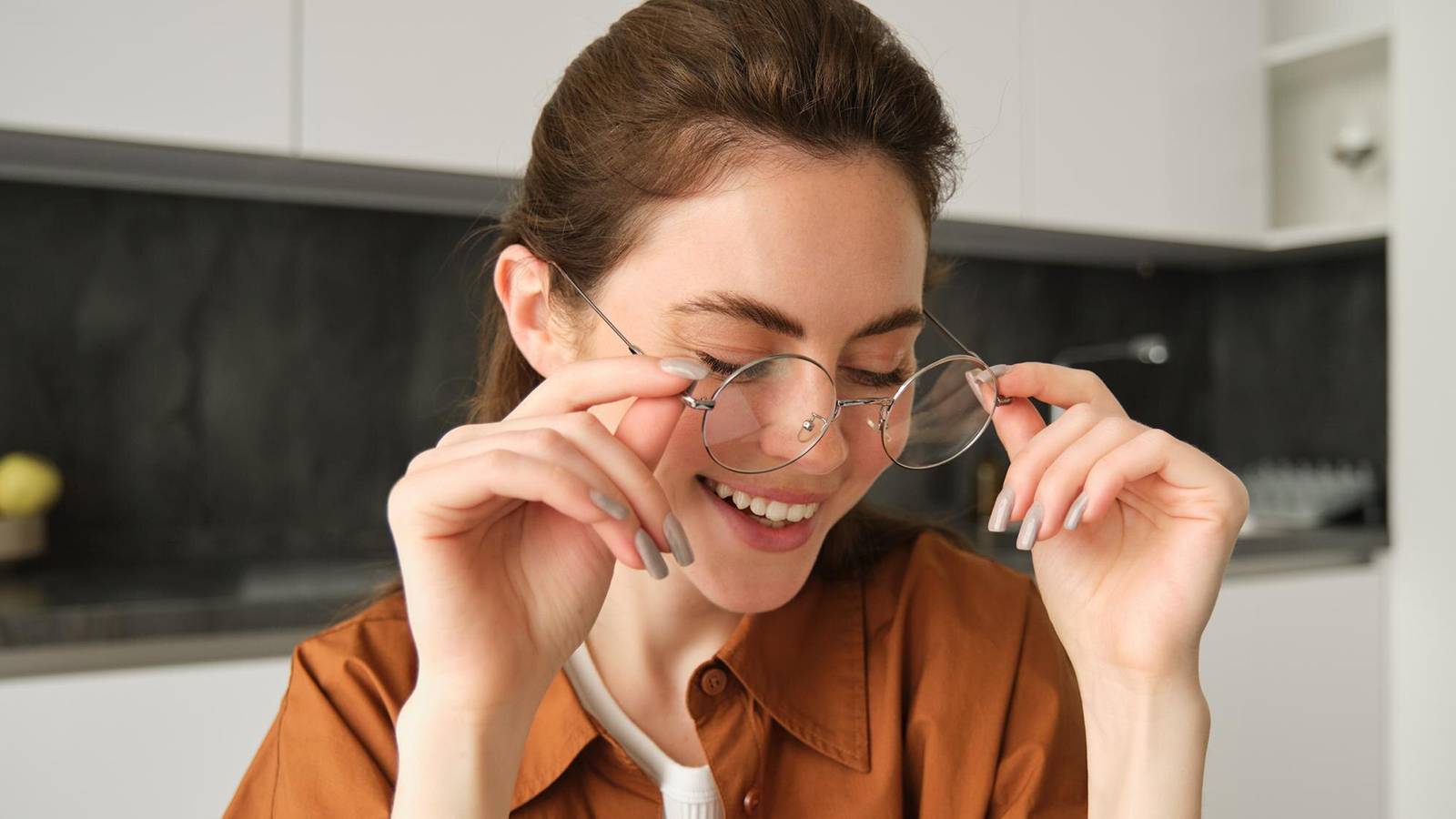 Happy woman adjusting clear glasses for comfort and everyday eye protection.