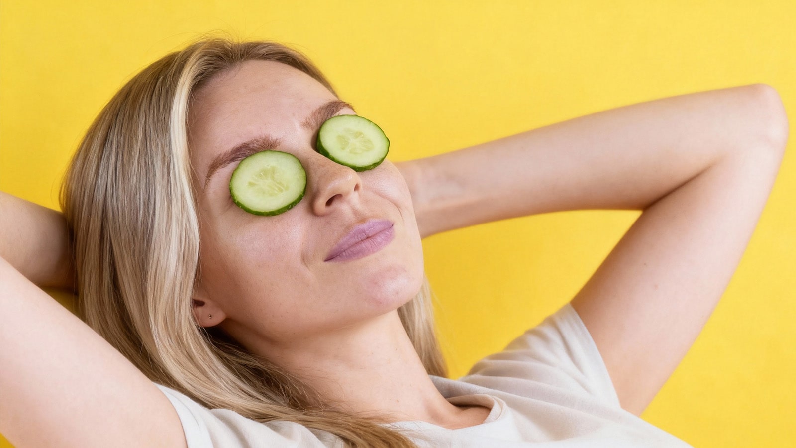 Woman using chilled cucumber slices to soothe and reduce eyeglass nose marks
