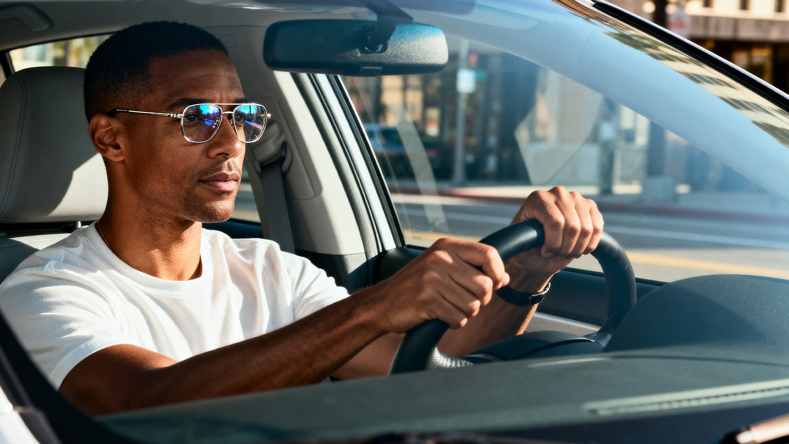 A driver wearing stylish prescription glasses safely operates a car, fulfilling the DMV corrective lenses requirement.