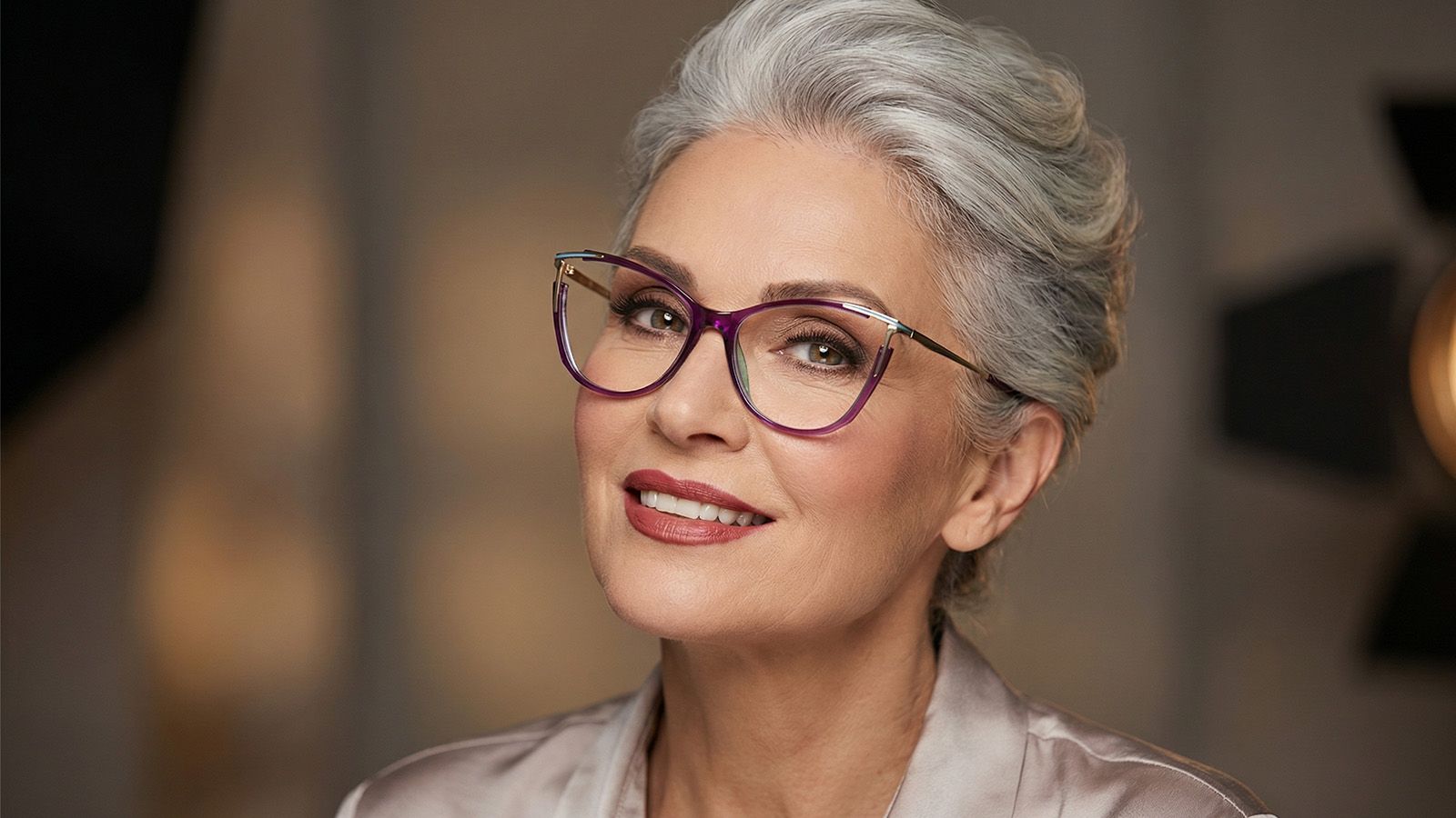 A sophisticated senior woman with grey hair wearing purple upswept cat-eye glasses that lift her look.