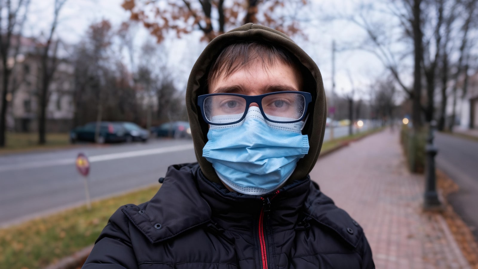 A person wearing a face mask outdoors struggles to see as their glasses are fogging up completely.