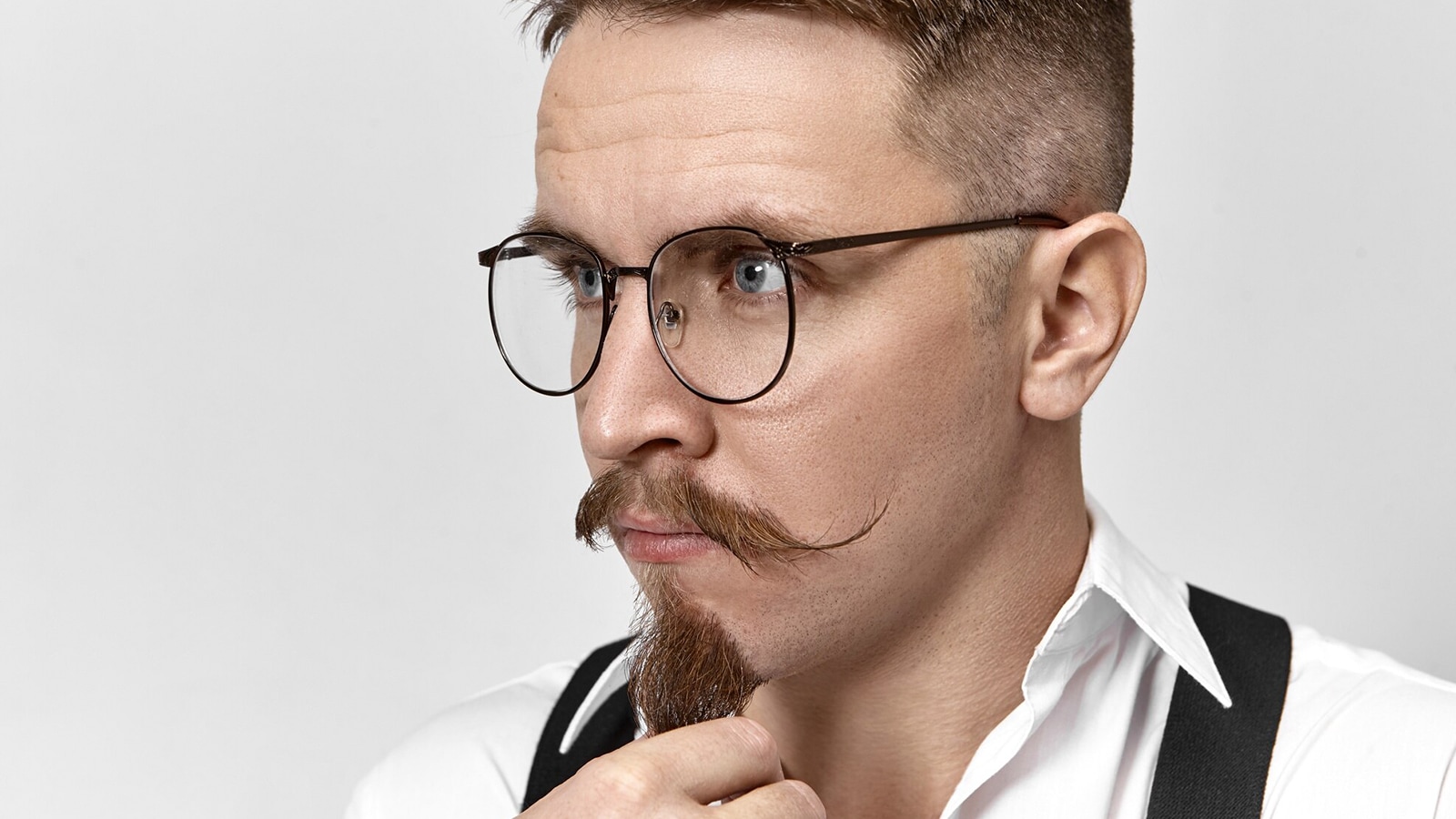 A man with a mustache and goatee, wearing round titanium frame glasses.