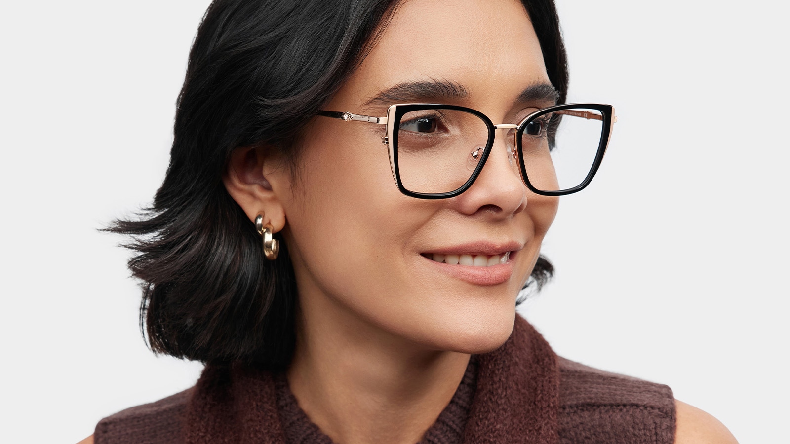A smiling woman wearing modern, stylish square-framed glasses over her contacts to express her personal style and complete her look.
