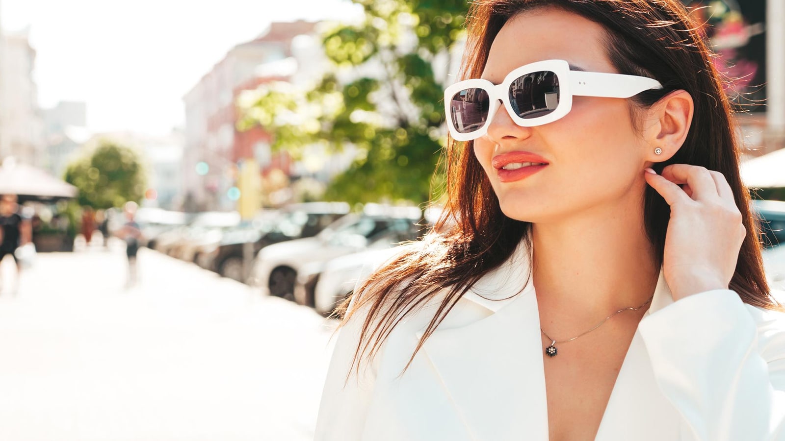A stylish woman wearing chic white sunglasses on a sunny city street, highlighting the confidence that comes with proper eye protection.