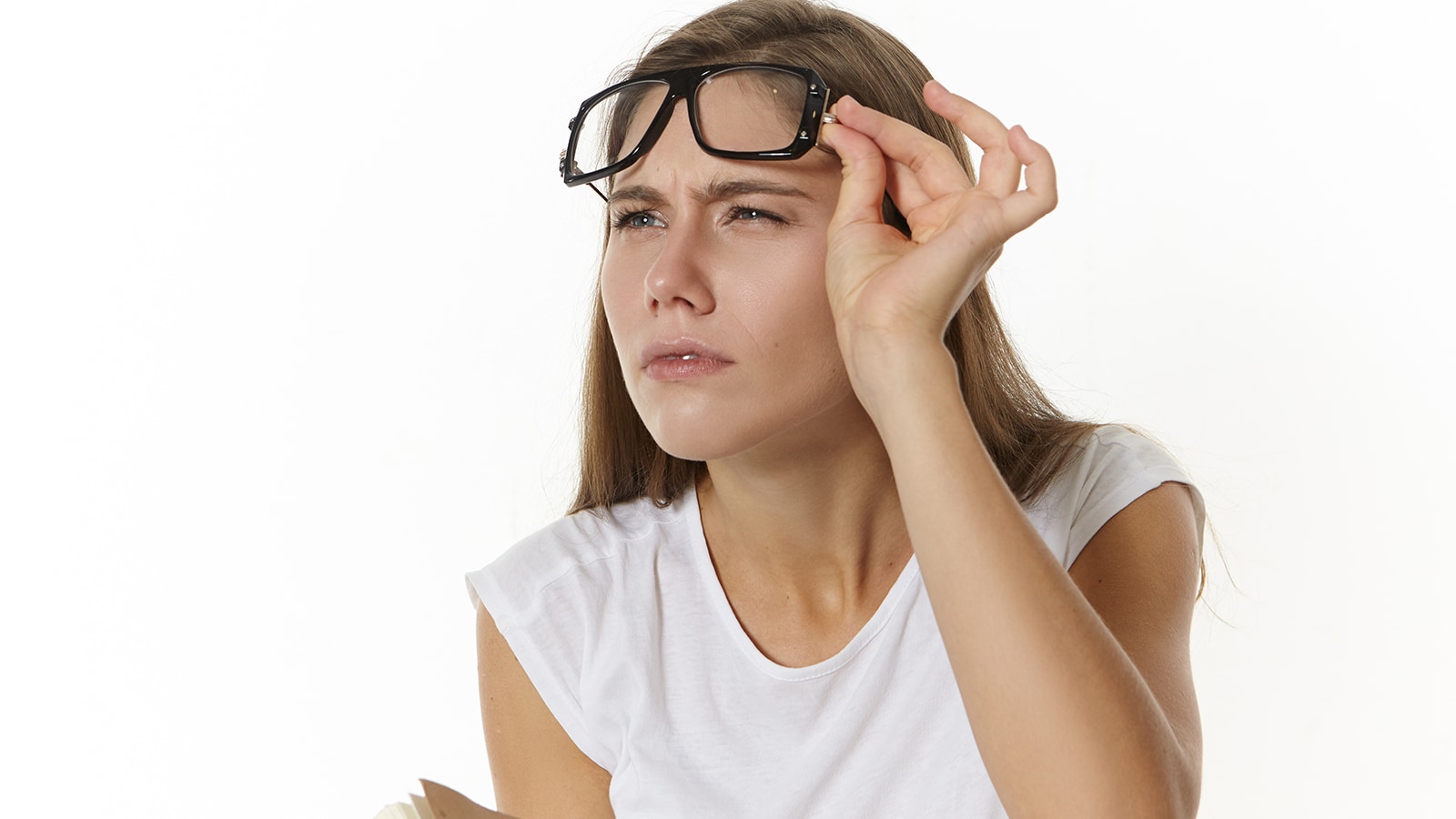 Woman squinting and lifting glasses, showing a common symptom of bilateral myopia and blurry distance vision.