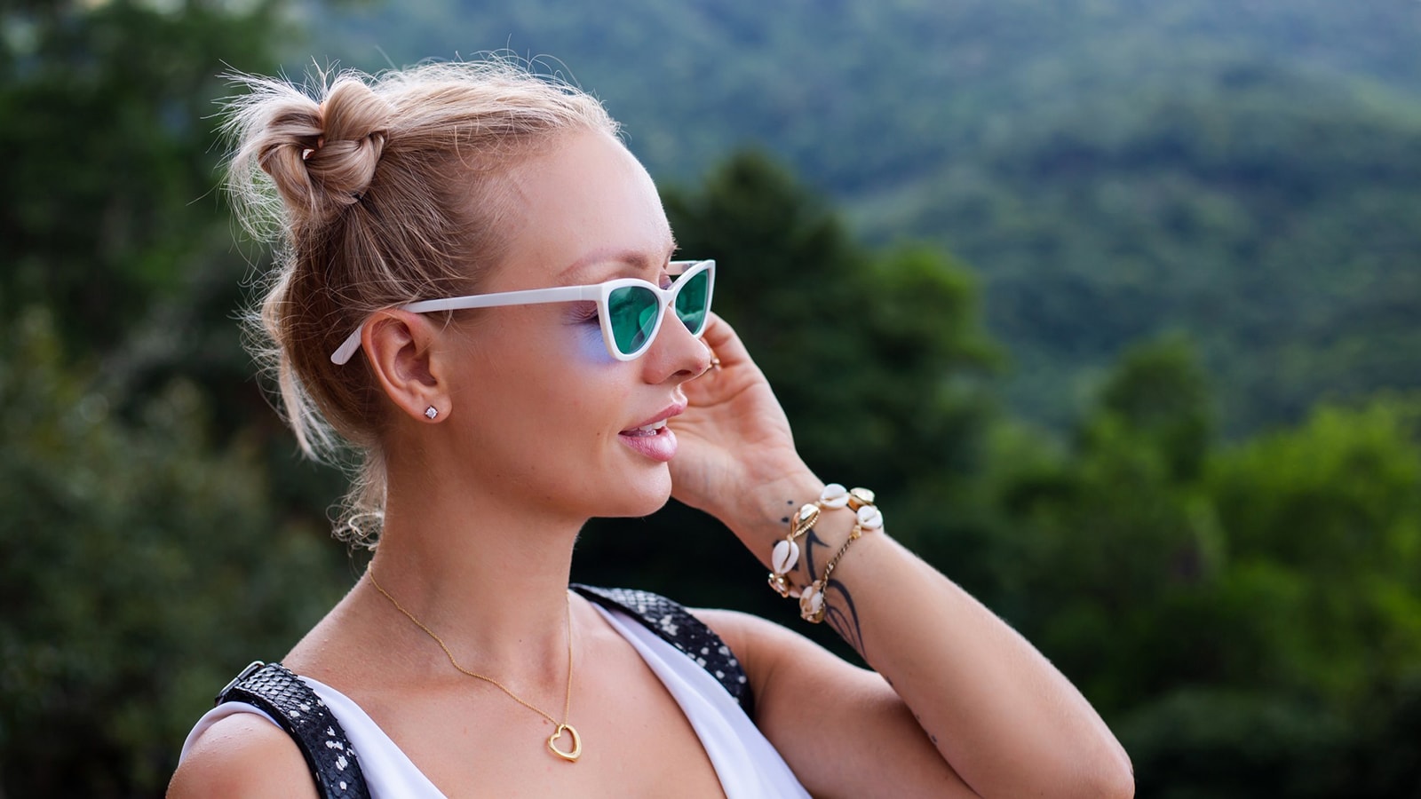 A woman enjoys a clear view of a lush landscape, showcasing how green lens sunglasses enhance vision for outdoor activities like hiking.
